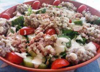 Μια πλούσια σαλάτα σε μεγάλο μπολ με στρώσεις μαρουλιού φαγόπυρου ντοματίνια και κομμάτια καπνιστού τόνου περιχυμένη με κρεμώδη σάλτσα