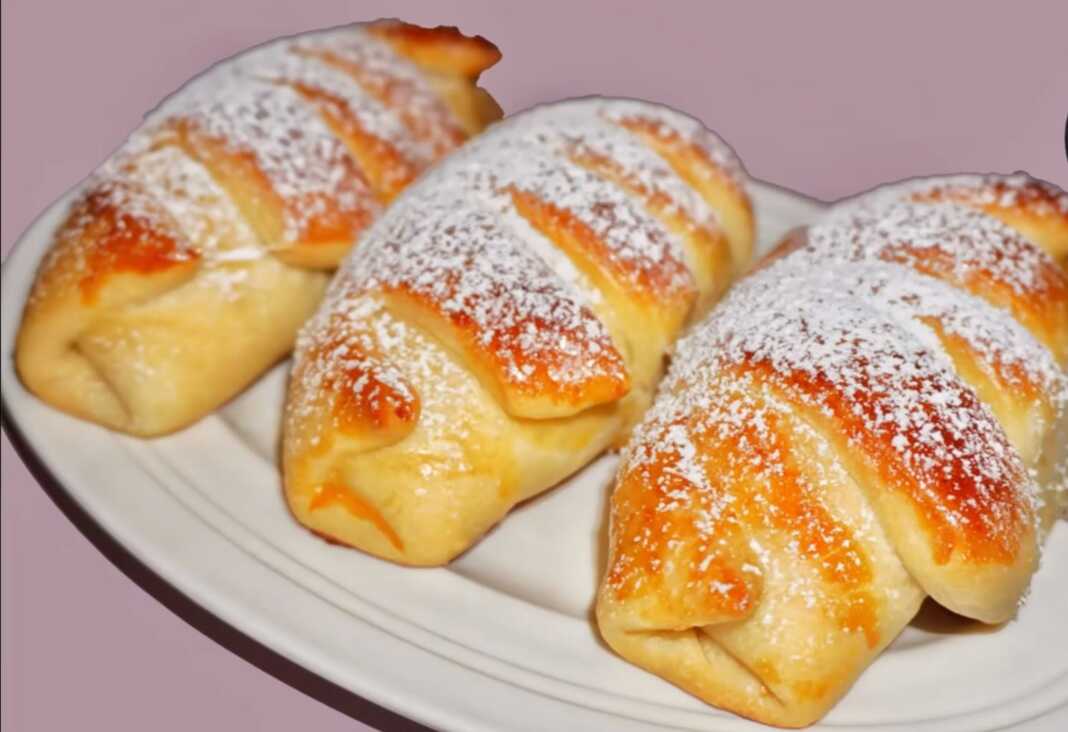 κρουσανάκια με κρέμα Πιάτο με χρυσαφένια, αφράτα κρουασανάκια, πασπαλισμένα με ζάχαρη άχνη, με διακριτική γέμιση κρέμας να φαίνεται στο εσωτερικό τους.