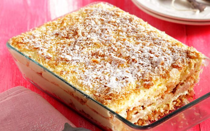 μιλφειγ Ένα ταψί εύκολου μιλφέιγ σε ένα πιάτο, με στρώσεις μπισκότων και κρέμας, πασπαλισμένο με άχνη ζάχαρη.