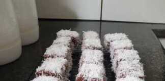 Lamingtons: Η Αυθεντική Συνταγή για τα Αυστραλιανά Κεκάκια Καρύδας Τετράγωνα αφράτα κεκάκια καλυμμένα με σκούρο γλάσο σοκολάτας και άσπρη τριμμένη καρύδα, τοποθετημένα σε σχάρα.