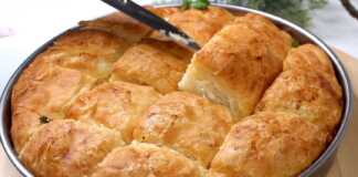 Ένα ροδοκοκκινισμένο τυρόψωμο στο ταψί, κομμένο σε τετράγωνα κομμάτια, με τις στρώσεις της ζύμης και της φέτας να ξεχωρίζουν.