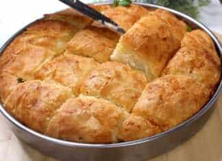 Ένα ροδοκοκκινισμένο τυρόψωμο στο ταψί, κομμένο σε τετράγωνα κομμάτια, με τις στρώσεις της ζύμης και της φέτας να ξεχωρίζουν.