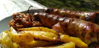 Λεμονάτες πατάτες φούρνου με κομμάτια χωριάτικου λουκάνικου, σερβιρισμένες σε ταψί.