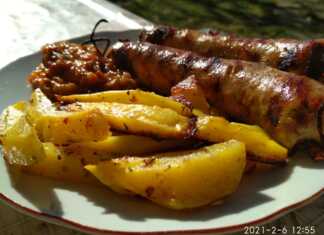 Λεμονάτες πατάτες φούρνου με κομμάτια χωριάτικου λουκάνικου, σερβιρισμένες σε ταψί.