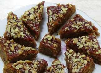 Ζεστό κέικ νηστείας σε οβάλ ταψί, αλειμμένο με μαρμελάδα και πασπαλισμένο με χοντροκομμένα καρύδια