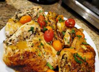 Κομμάτια ψημένου κοτόπουλου σερβιρισμένα σε πιάτο με κόκκινη σάλτσα, ντοματίνια και φρέσκα μυρωδικά.