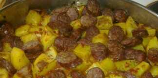 Ταψί με λουκάνικα κομμένα, πατάτες και πράσα ψημένα στο φούρνο με χρυσαφένια κρούστα τυριού.