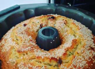 Μια ψηλή και αφράτη τυρόπιτα σε σχήμα κέικ με χρυσαφένια κρούστα κομμένη σε φέτες που αποκαλύπτουν τα κομμάτια τυριού και τις σταφίδες