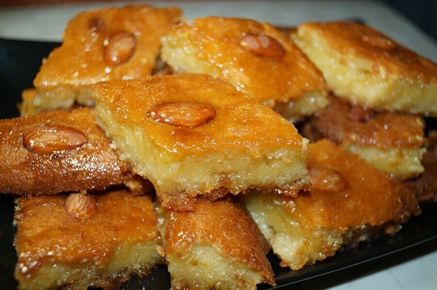 basbousa Τετράγωνα κομμάτια αραβικής Μπασπούσας με ένα ολόκληρο αμύγδαλο στο κέντρο κάθε κομματιού καλά σιροπιασμένα