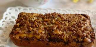 Ένα ταψι υγρού κέικ με μήλα και καρυδιά, καλυμμένο με λευκό γλάσο ζάχαρης.