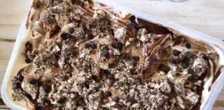 Ενα μπολ παγωτού με ανοιχτό καφέ χρώμα, με ορατά κομμάτια χαλβά και σκούρες ραβδώσεις σοκολάτας,