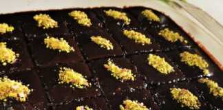 Ένα κομμάτι ζουμερής σοκολατόπιτας περιχυμένο με σοκολατένιο σιρόπι και πασπαλισμένο με αλεσμένα φυστίκια.