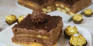 Ένα κομμάτι λαχταριστού κέικ Rocher χωρίς ψήσιμο, με στρώσεις κρέμας Nutella και επικάλυψη ganache σοκολάτας με φουντούκια.