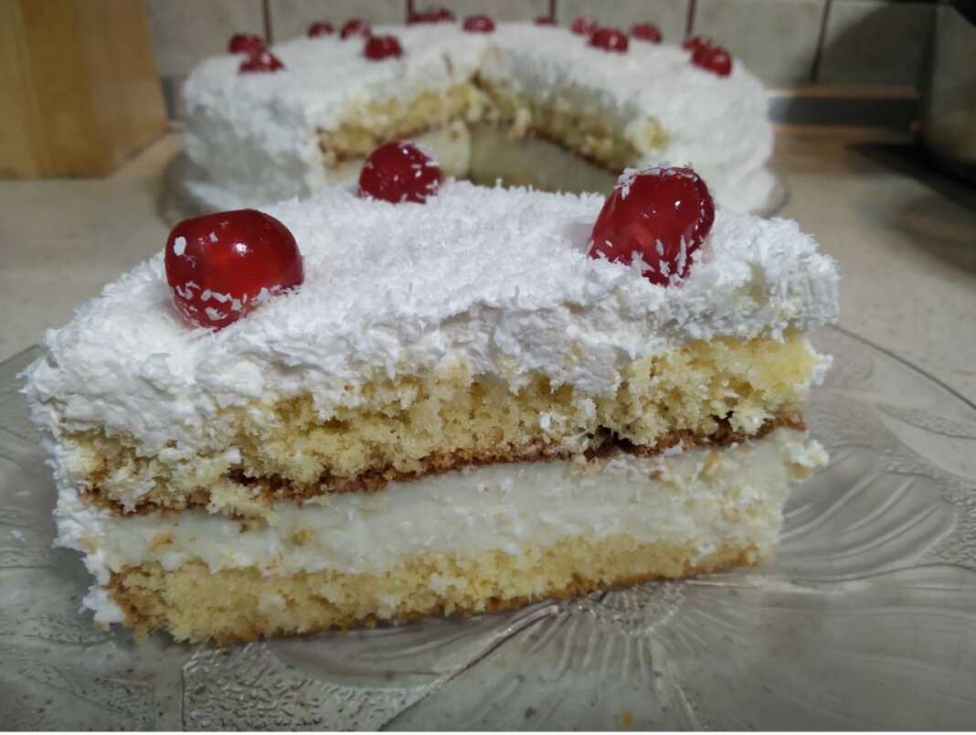 Μια μεγάλη φέτα από την **Τούρτα Χιονούλα** με τις στρώσεις κρέμας και σαντιγί.