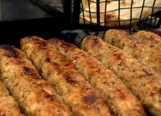 Σειρά από καλοψημένα κεμπάπ κοτόπουλου πάνω σε λαδόκολλα σερβιρισμένα με πίτες και δροσερό τζατζίκι