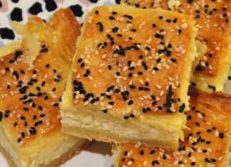 Παραδοσιακή κρητική τυρόπιτα σε ταψί, με χρυσαφένια κρούστα πασπαλισμένη με σουσάμι και μαυροκούκι, έτοιμη για σερβίρισμα.