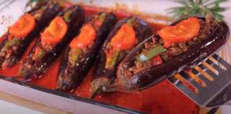 Ένα πυρέξ γεμάτο μελιτζάνες κομμένες στη μέση και γεμιστές με κιμά, ντομάτα και πιπεριά, έτοιμες για ψήσιμο ή ψημένες.