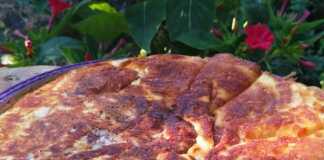 Μια ολόκληρη Τυρόπιτα στο τηγάνι, με χρυσαφένιο χρώμα, σερβιρισμένη σε ξύλινη πιατέλα