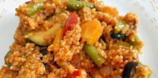 Πιάτο με πολύχρωμο κους-κους αναμεμειγμένο με διάφορα ψιλοκομμένα λαχανικά, όπως πιπεριές, κολοκυθάκια και καρότα.