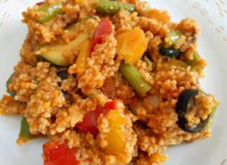 Πιάτο με πολύχρωμο κους-κους αναμεμειγμένο με διάφορα ψιλοκομμένα λαχανικά, όπως πιπεριές, κολοκυθάκια και καρότα.