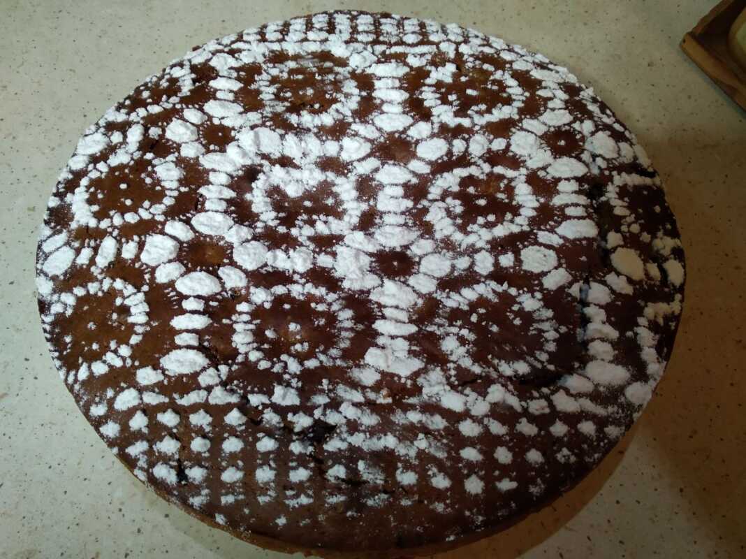 Μία ολόκληρη Φανουρόπιτα με 9 υλικά, πασπαλισμένη με ζάχαρη άχνη, σε πιατέλα σερβιρίσματος