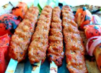 Ζουμερά Adana κεμπάπ περασμένα σε πλατύ σουβλάκι ψημένα στη σχάρα και σερβιρισμένα με σαλάτα κρεμμυδιού και ψητές πιπεριές