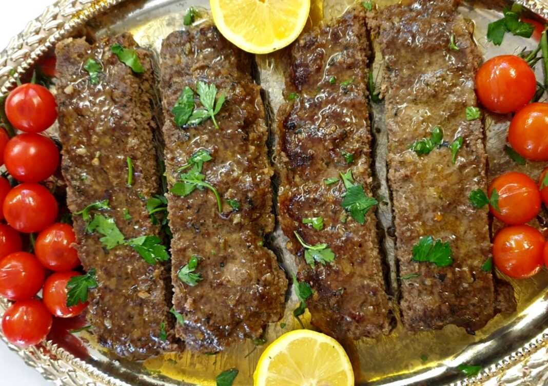 kempap fournou Ένα ταψί γεμάτο με ψημένο κεμπάπ κομμένο σε λωρίδες, συνοδευόμενο από ψημένα ντοματίνια.