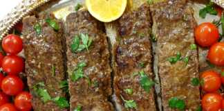 Ένα ταψί γεμάτο με ψημένο κεμπάπ κομμένο σε λωρίδες, συνοδευόμενο από ψημένα ντοματίνια.