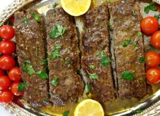 Ένα ταψί γεμάτο με ψημένο κεμπάπ κομμένο σε λωρίδες, συνοδευόμενο από ψημένα ντοματίνια.