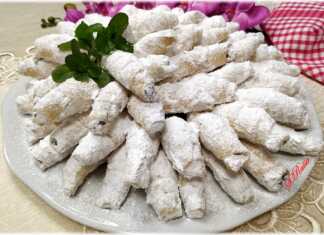 Πολλά μικρά κρουασανάκια καρυδιού, πασπαλισμένα πλούσια με ζάχαρη άχνη, σερβιρισμένα σε πιατέλα.