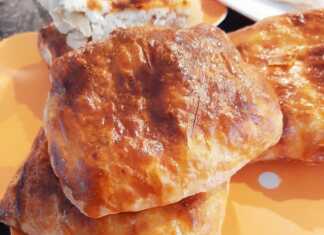 Ατομικές τυρόπιτες με χρυσαφένιο, τραγανό φύλλο μπουγάτσας που θρυμματίζεται, τοποθετημένες σε σειρά πάνω σε λαδόκολλα.