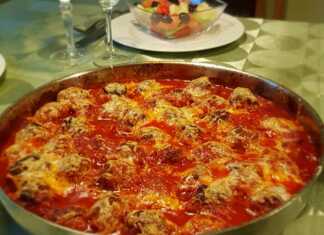 Ζουμερά κεφτεδάκια σε κόκκινη σάλτσα ντομάτας, καλυμμένα με λιωμένο χρυσαφένιο κίτρινο τυρί, μέσα σε ταψί φούρνου.