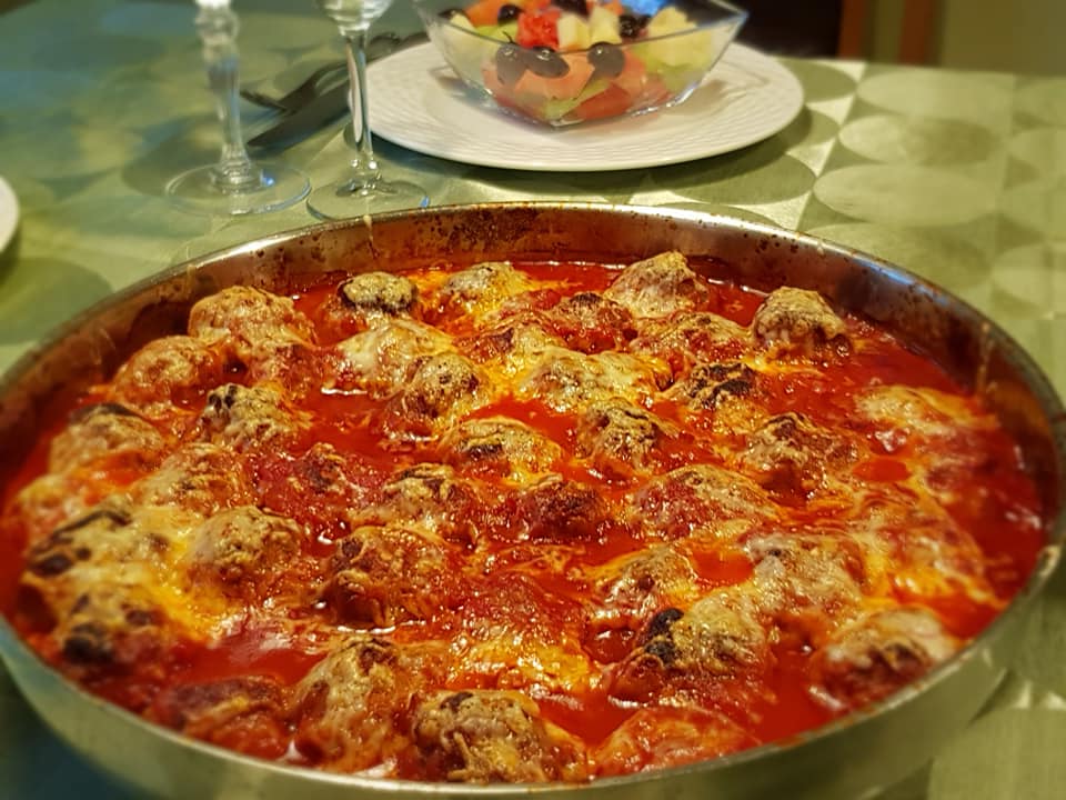 keftedakiaKokkiniSaltsa Ζουμερά κεφτεδάκια σε κόκκινη σάλτσα ντομάτας, καλυμμένα με λιωμένο χρυσαφένιο κίτρινο τυρί, μέσα σε ταψί φούρνου.