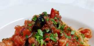 Μακαρόνια με μπακαλιάρο και ντομάτα. Πιάτο με μακαρόνια, κομμάτια μπακαλιάρου, κόκκινη σάλτσα ντομάτας, ελιές και μαϊντανό, έτοιμο για σερβίρισμα.