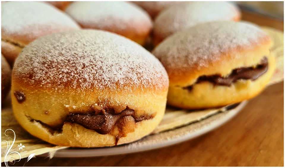 ntonats sokolatas1 Αφράτα ντόνατς γεμιστά με σοκολάτα, πασπαλισμένα με άχνη ζάχαρη σε πιατέλα.