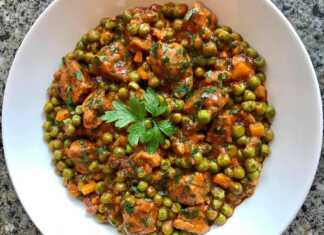 Ένα πιάτο με χοιρινό κομμάτια και πράσινο αρακά σε κόκκινη σάλτσα, πασπαλισμένο με μαϊντανό.