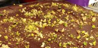 Τριώροφη καρυδόπιτα: βάση σιροπιασμένης καρυδόπιτας, παχιά στρώση κρέμας ζαχαροπλαστικής και επάνω στρώση γκανάς σοκολάτας, γαρνιρισμένη με χοντροκομμένα καρύδια.