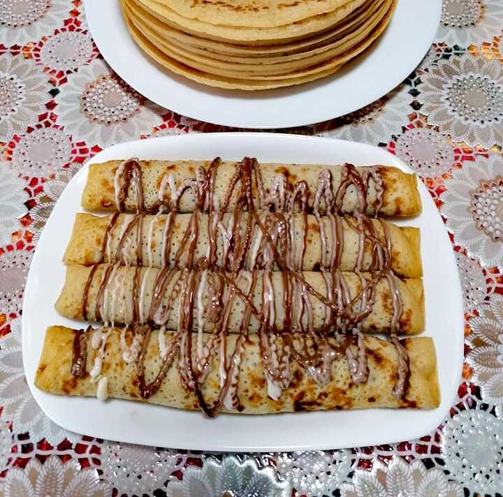 krepesSokolata Μια τυλιγμένη κρέπα σοκολάτας γεμιστή με λευκή κρέμα και θρυμματισμένα μπισκότα, με επιπλέον λιωμένη σοκολάτα από πάνω.