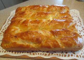 Χρυσαφένιο στριφτό τυρόψωμο στο ταψί με εμφανείς τις στρώσεις του βουτύρου και του τυριού και γυαλιστερή κρούστα από κρόκο αυγού