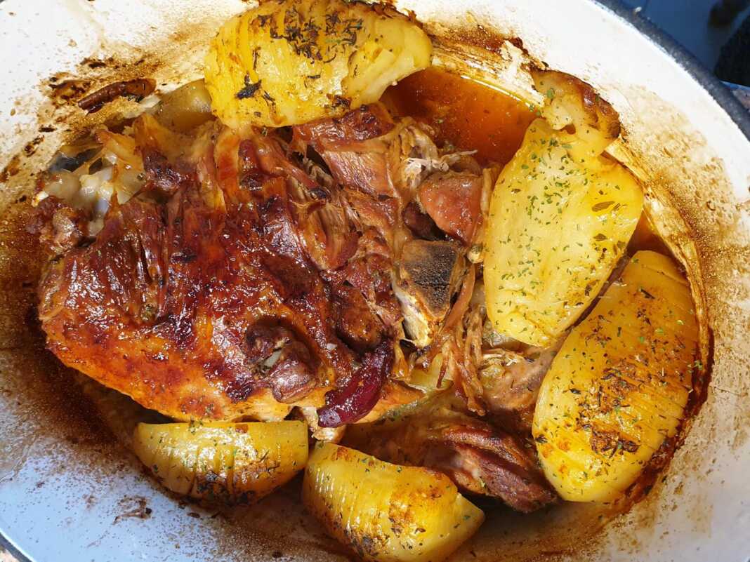 Ένα ολόκληρο κομμάτι αρνί στο φούρνο με πατάτες, ψημένο και ροδισμένο, μέσα σε ταψί