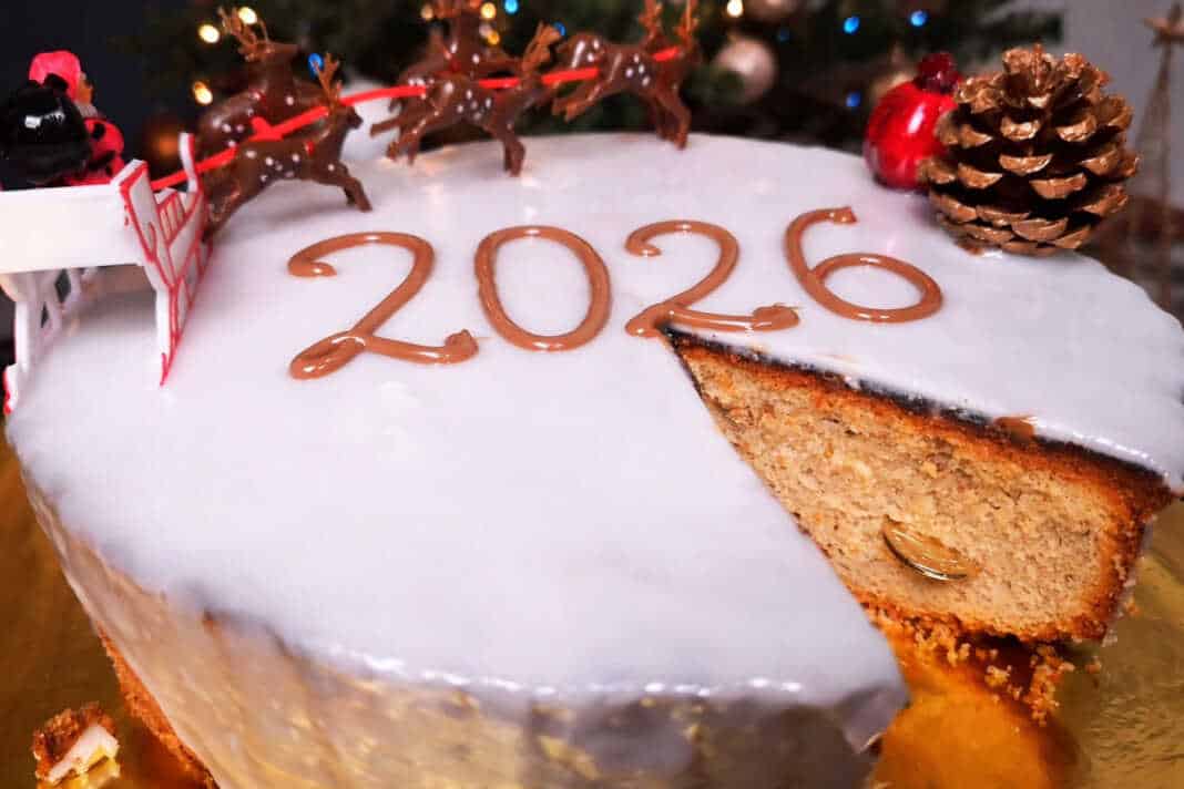 Μια εντυπωσιακή βασιλόπιτα κέικ καλυμμένη με λευκό γυαλιστερό γλάσο και στολισμένη για την υποδοχή του νέου έτους