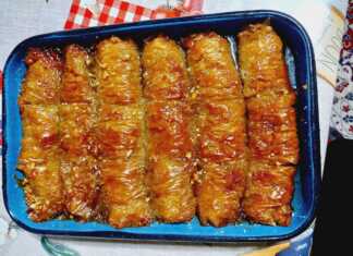 Σιροπιασμένα ρολά μπακλαβά με καρύδι και σουσάμι τοποθετημένα σε σειρά σε ταψί