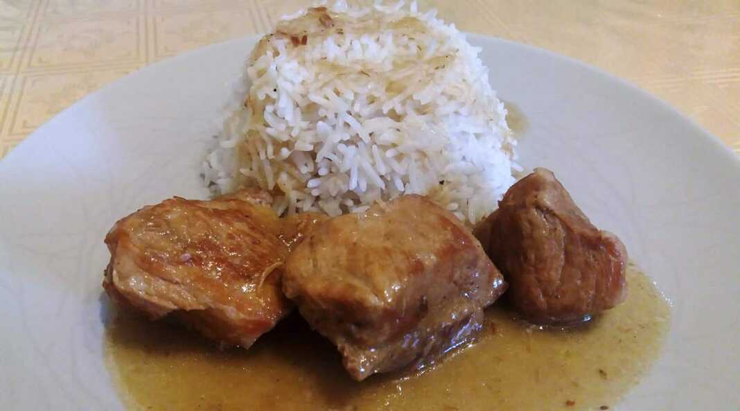 Ένα πιάτο με χοιρινό κομμένο σε μερίδες, περιχυμένο με λαδολέμονο και ρίγανη, δίπλα σε λευκό ρύζι μπασμάτι.