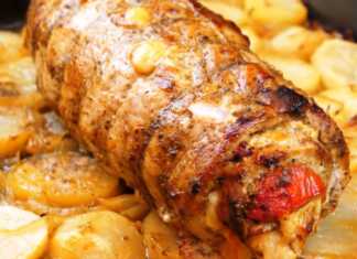 Μεγάλο ψημένο χοιρινό ρολό, δεμένο με σπάγκο, τοποθετημένο σε πιατέλα με ψημένες πατάτες, κρεμμύδια και ντοματίνια.