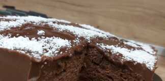 Ένα κομμάτι λαχταριστού κέικ σοκολάτας, περιχυμένο με γυαλιστερό γλάσο κακάο και πασπαλισμένο με τριμμένη καρύδα.