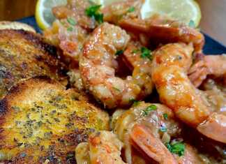 Μεγάλες, ροδισμένες γαρίδες στη σχάρα, περιχυμένες με χρυσαφένια σάλτσα σκόρδου-βουτύρου, γαρνιρισμένες με φρέσκο μαϊντανό, με φρυγανισμένο ψωμί δίπλα τους.