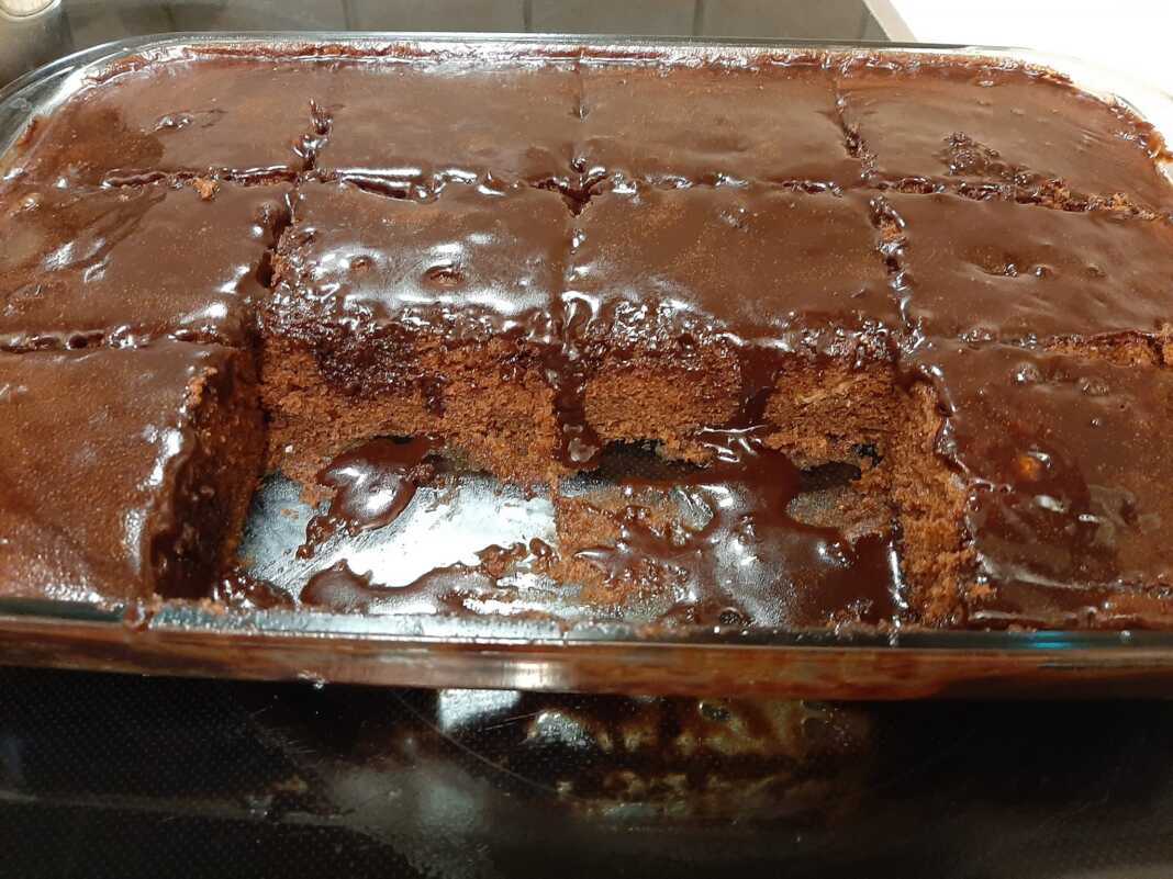 Λαχταριστό γλυκό σοκολατένιο κομμένο σε τετράγωνα κομμάτια, με πλούσια, γυαλιστερή επικάλυψη σοκολάτας.