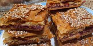 Κομμάτια Παστουρμαδόπιτα, φρεσκοψημένη, με χρυσαφένια κρούστα και σουσάμι στην επιφάνεια.