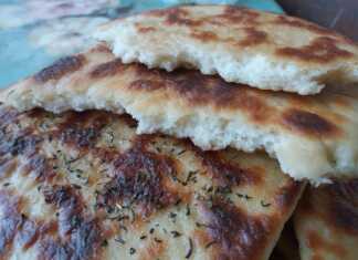 Ζεστές πίτες σκόρδου αλειμμένες με σκορδοβούτυρο και πασπαλισμένες με αλάτι πάνω σε ξύλινη επιφάνεια