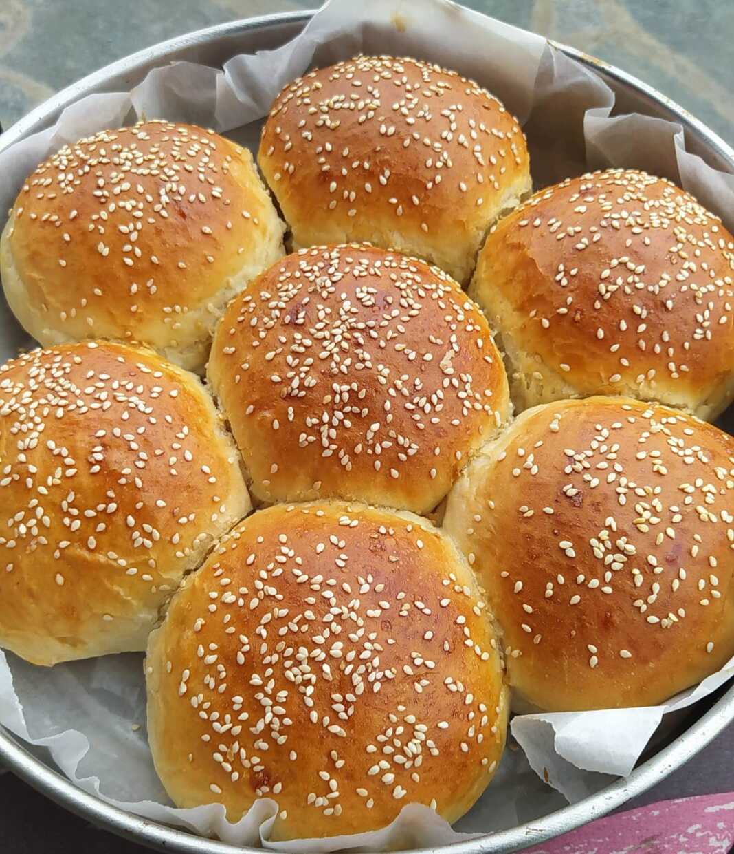 psomiMargarita Ένα ολόκληρο, χρυσαφένιο, στρογγυλό ψωμί σε σχήμα μαργαρίτας, πασπαλισμένο με σουσάμι, πάνω σε ξύλινη επιφάνεια.